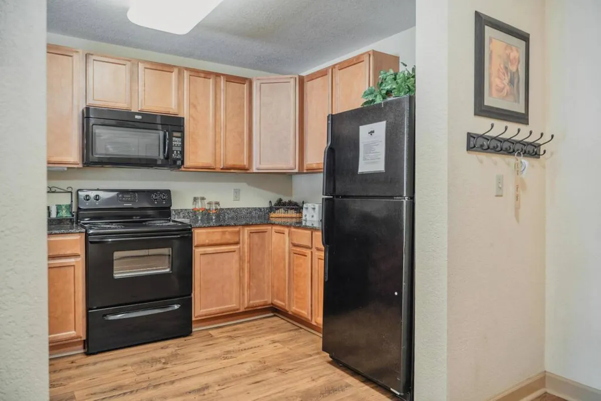 A kitchen scene showcasing modern appliances, granite countertops, and wooden cabinetry. The arrangement and cleanliness suggest the kitchen is ready for cooking family recipes or hosting dinner parties.