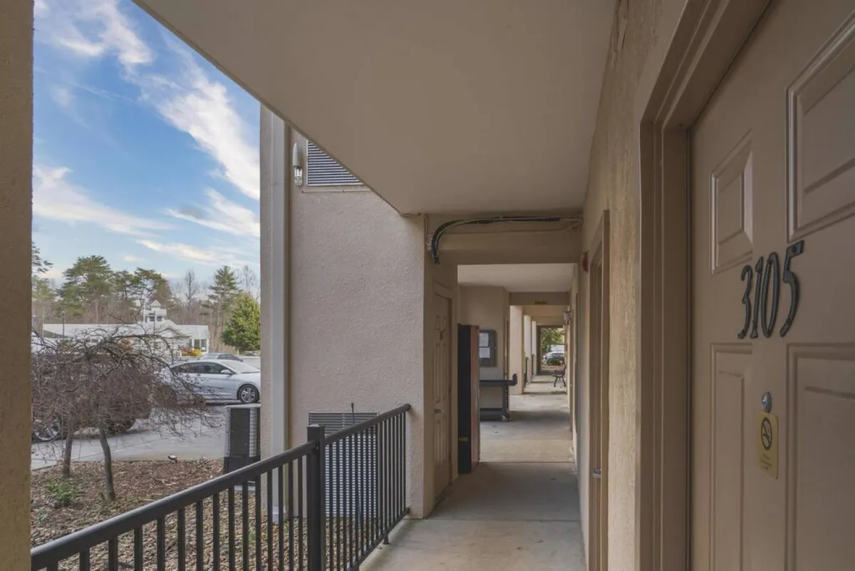 An inviting exterior walkway scene featuring the entrance to condo unit 3105, a sturdy railing, and a welcoming path. The vibe is friendly and accessible, evoking the feeling of coming home after a day out.