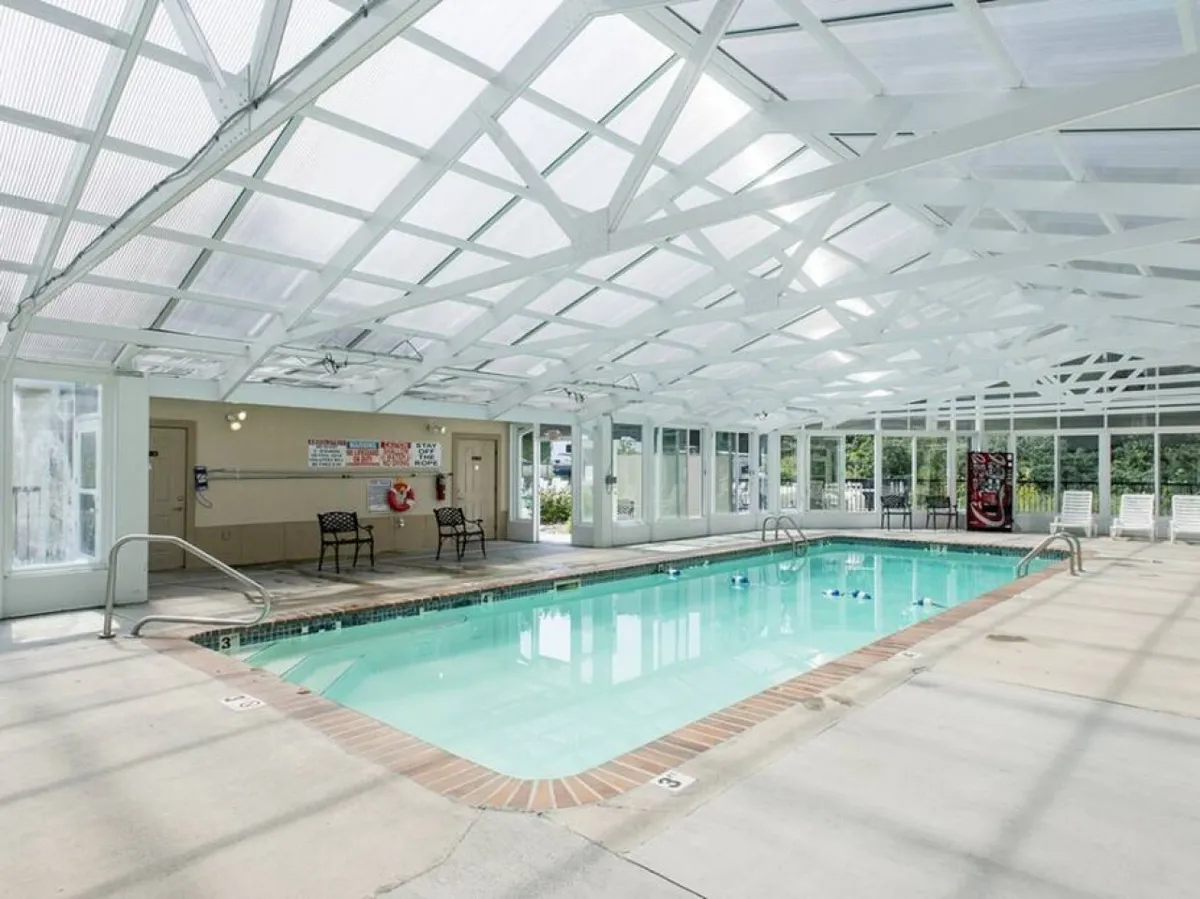 This image features an inviting indoor pool with a white lattice ceiling and poolside chairs, providing a relaxing atmosphere for year-round swimming and socializing.